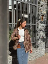 Falda midi de denim con elastano, corte recto y tajo frontal. Presenta bolsillos delanteros de cuero en color tostado y diseño clásico.