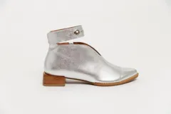 Botín de cuero color borgoña con taco bajo, corte en V en el empeine, pulsera con detalles metálicos y cierre lateral.