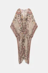 Vestido tipo túnica de viscosa con escote en pico y mangas tipo capa. Presenta un diseño estampado con motivos ornamentales en tonos tierra, beige y rosado, con pliegues en la cintura y bajo asimétrico.