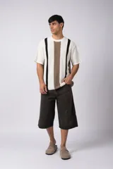 Remera de punto con textura piqué, manga corta y cuello redondo. Presenta un diseño de rayas verticales en tonos crudo, marrón y negro.