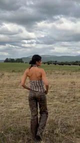 Top de cuello halter con diseño drapeado en el frente, confeccionado en tela con estampado de cuadros. Presenta un ajuste entallado con elásticos laterales y espalda descubierta.