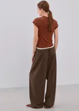 Camiseta ajustada color marrón con mangas cortas y terminaciones con volados delicados en cuello, mangas y dobladillo.
