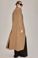 Abrigo largo entallado de Zara Woman Collection, confeccionado en mezcla de lana color tostado. Presenta cuello con solapa de muesca, mangas largas, bolsillos con solapa en el frente, forro interior y cierre frontal de dos botones oscuros.