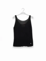 Top tejido sin mangas en punto canalé, color negro con hilos metálicos Lurex que le dan un brillo sutil. Presenta escote bote y un dije metálico en color oro rosado.