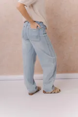 Jean de calce relajado y pierna amplia color beige, con tiro alto y detalle de recortes y costuras visibles.