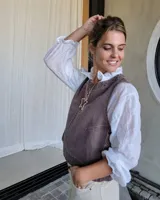 Chaleco de corte recto y largo a la cintura, confeccionado en denim con estampado de rayas verticales en tonos azul y blanco. Presenta cuello redondo y costuras visibles que definen su estructura.