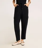 Pantalón negro de crepé con corte carrot, cintura alta con elástico en la parte trasera y lazo en la delantera, bolsillos delanteros con detalle metalizado y bolsillos cargo laterales.