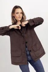 Chaqueta de gamuza color tostado con cuello camisero, cierre frontal de botones y bolsillos delanteros con solapa.