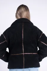 Campera de corderito color beige con ribetes y detalles en símil cuero marrón, cuello alto con hebilla decorativa, bolsillos laterales y cierre frontal.