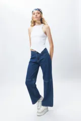 Top de algodón blanco sin mangas con cuello halter y bajo asimétrico en punta diagonal. Presenta un tejido de punto acanalado y un diseño inspirado en la estética de los años 2000.