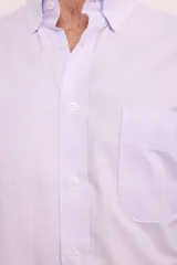 Camisa de corte clásico confeccionada en algodón, con diseño de rayas verticales finas en color rosa sobre fondo blanco. Presenta cuello abotonado, cierre frontal con botones, mangas largas con puños abotonados y un bolsillo en el pecho con el logo de la marca bordado.