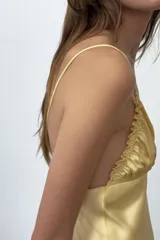 Vestido midi de tejido satinado en color amarillo, con escote en pico, tirantes finos ajustables, detalles de frunces en el pecho y falda de corte fluido.