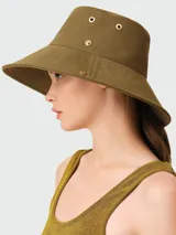Sombrero tipo bucket color verde oliva, confeccionado en algodón, con detalles de ojales metálicos dorados y logo de la marca en el lateral.
