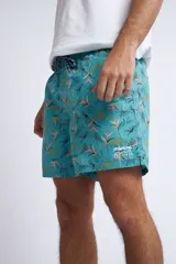 Short de baño con cintura elástica y cordón ajustable, confeccionado en tela ligera de secado rápido. Presenta un estampado botánico integral en tonos amarillos, blancos y azules, con dos bolsillos delanteros y uno posterior.