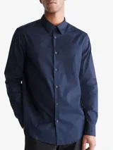 Camisa de vestir azul marino de manga larga, con cuello clásico y cierre con botones. Presenta un logo bordado en el pecho. Corte entallado.