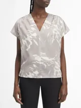 Blusa de satén gris con estampado abstracto en blanco, escote en V y mangas cortas.