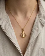 Dije de acero con baño de oro en forma de ancla con detalle de soga grabada.