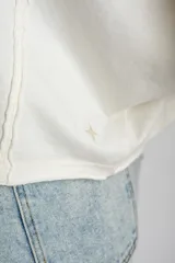 Remera oversize de algodón blanco crudo, con cuello redondo y mangas cortas anchas de corte relajado.