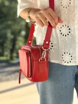 Bandolera roja de cuero con forro de tela, con bolsillo interior y exterior.