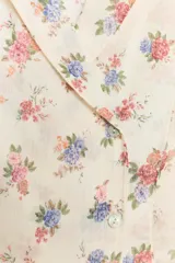 Camisa de cuello solapa y manga larga, con estampado de flores y cierre frontal cruzado.