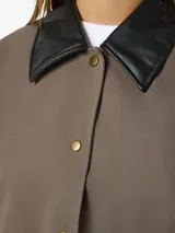 Campera de estilo worker color marrón topo, con cuello camisero y puños en contraste de color negro. Presenta cierre frontal con botones a presión metálicos, dos bolsillos frontales con solapa y diseño de corte holgado.