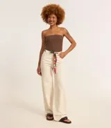 Pantalón wide leg color crudo, confeccionado en sarga de algodón, con trabillas en la cintura, cierre tradicional, bolsillos y costura contrastante aparente. Incluye cinturón pañuelo estampado.