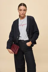 Sobrecamisa de jean azul oscuro, de calce relajado, escote en V, bolsillos delanteros aplicados, cierre frontal con botones metálicos y pespuntes en contraste.