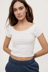 Remera blanca de corte ajustado y largo cropped, con escote redondo amplio y mangas cortas.