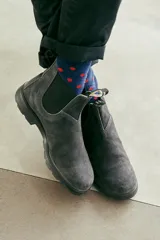 Botas Blundstone modelo 1910, de gamuza gris, con elásticos laterales negros, suela de goma negra y tiradores de tela con logo en la parte trasera.