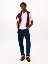 Chomba blanca de corte regular confeccionada en algodón orgánico con un toque de elastano, cuello tipo chomba y cartera de dos botones. Tiene el logo de Tommy Hilfiger bordado en el pecho.