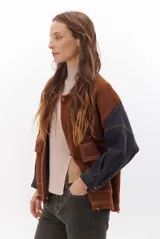 Campera color caramelo con mangas de denim azul oscuro. Presenta cuello alto, cierre frontal con botones, cuatro bolsillos delanteros con solapa y pespuntes blancos decorativos.