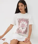 Remera blanca de manga corta y cuello redondo, confeccionada en algodón. Cuenta con una estampa frontal localizada de inspiración bohemia con un marco paisley en tonos rosados y marrones, y el texto "Free Spirit" en el centro.