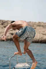 Short de baño con estampado ornamental de estilo paisley y rayas verticales en tonos azules, verdes y blancos. Cuenta con cintura elástica, dos bolsillos laterales y un bolsillo trasero.