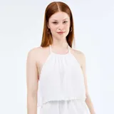 Vestido corto blanco sin mangas, con cuello halter y diseño de volantes escalonados en capas superpuestas.