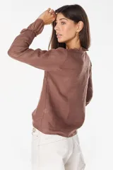 Blusa de lino italiano color beige con escote en V y detalles de volados en el cuello y los puños. Presenta cierre frontal con botones de nácar y mangas largas.