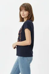 Remera de algodón color beige, de manga corta con vuelta, cuello redondo y estampa frontal de flores con lazo en tonos azules y celestes.
