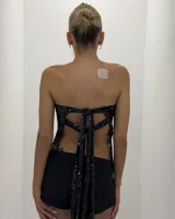 Top strapless tipo bando de color negro, íntegramente bordado con lentejuelas al tono. Cuenta con un detalle de flecos tejidos en el ruedo.