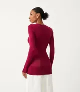 Blusa de punto de corte alargado, color negro, con escote redondo, manga larga y detalle de botones decorativos en los puños.