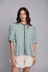 Chaqueta de tusor de algodón color menta, con mangas abullonadas, cuello redondo y cierre frontal con botones al tono. Presenta un diseño con estructura en hombros y espalda, y un corte con vuelo en la parte inferior.