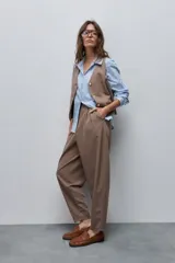 Pantalón marrón de tiro alto y silueta amplia, confeccionado con pinzas en el frente y bolsillos laterales.