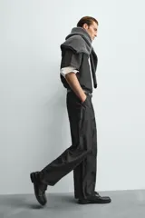 Pantalón de jeans de algodón ligero, color negro lavado, con corte balloon fit (holgado y ancho). Presenta pliegues frontales marcados en la cintura y cierre frontal de cremallera y botón.