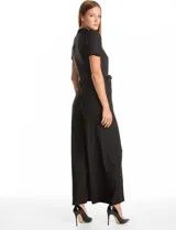 Enterito de seda fría color negro, con cuello a la base fruncido, escote en V con botones metálicos y detalle plisado vertical en el frente. Presenta mangas cortas con terminación fruncida, cintura con lazo de ajuste y pantalón de pierna ancha con caída fluida.