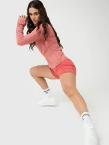 Polera deportiva de manga larga en color rosa melange, con cuello alto y cierre frontal parcial. Presenta un diseño ajustado con costuras visibles y aberturas para los pulgares en los puños.