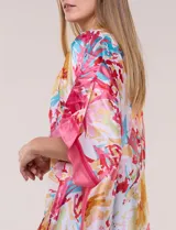 Kimono de satén ligero con estampado floral en tonos rosados, amarillos y celestes, de silueta amplia y diseño abierto al frente con mangas cortas amplias.