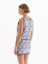 Chaleco de punto semiliviano con diseño jacquard en tonos blanco, azul y rojo, escote en V profundo y cierre frontal con tiras para anudar.