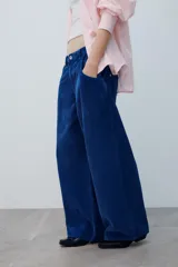Pantalón de tiro medio confeccionado en pana color azul, de corte baggy con pierna ancha, estilo clásico de cinco bolsillos y cierre frontal con cremallera y botón metálico.