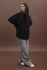 Sweater de punto negro con diseño de trenzas verticales, cuello alto y corte holgado de estilo oversize.