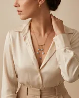 Collar de acero con baño de oro, compuesto por una cadena fina y un dije central en forma de arco del que cuelgan cinco dijes pequeños con diseño de ojo turco.