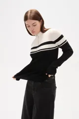 Polera de punto acanalado con diseño bicolor en blanco y negro, cuello alto con cierre frontal y manga larga.