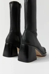 Botas negras de caña alta, realizadas en piel de cordero italiano, con puntera redonda, cierre lateral y tacón cuadrado.